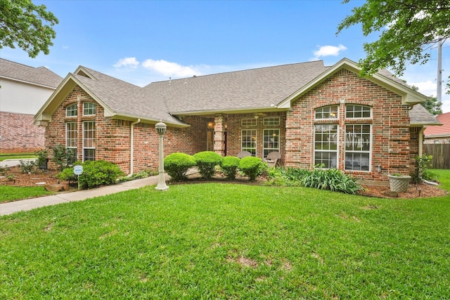 single story home with brick siding, roof with shingles, and a front yard