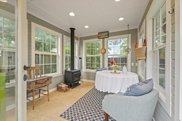 sunroom / solarium featuring plenty of natural light, a wood stove, tile patterned floors, and recessed lighting