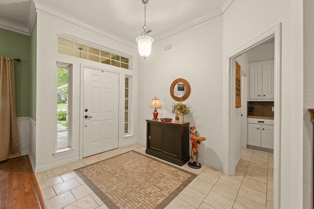foyer entrance with crown molding, baseboards, and light tile patterned flooring