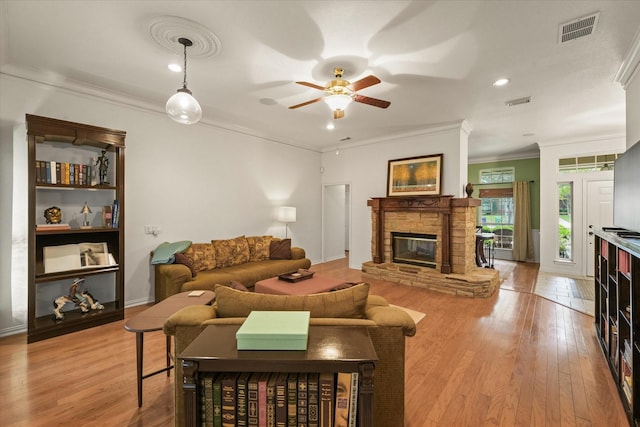 living area featuring a ceiling fan, visible vents, ornamental molding, and light wood-style flooring