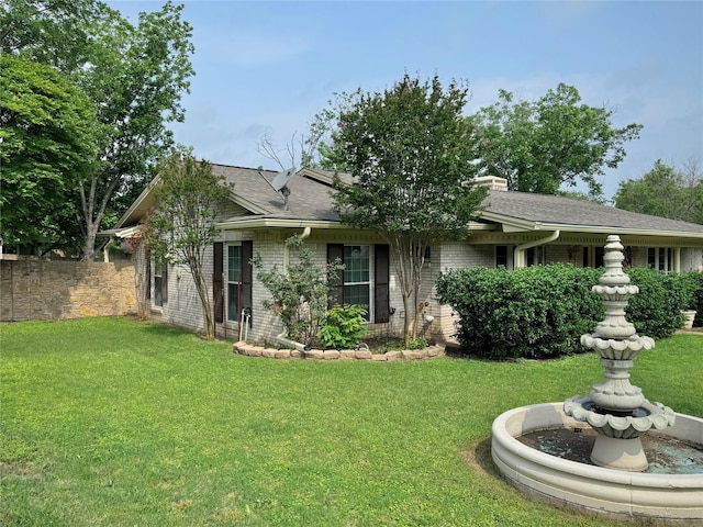 ranch-style home featuring fence, a chimney, a front lawn, and brick siding
