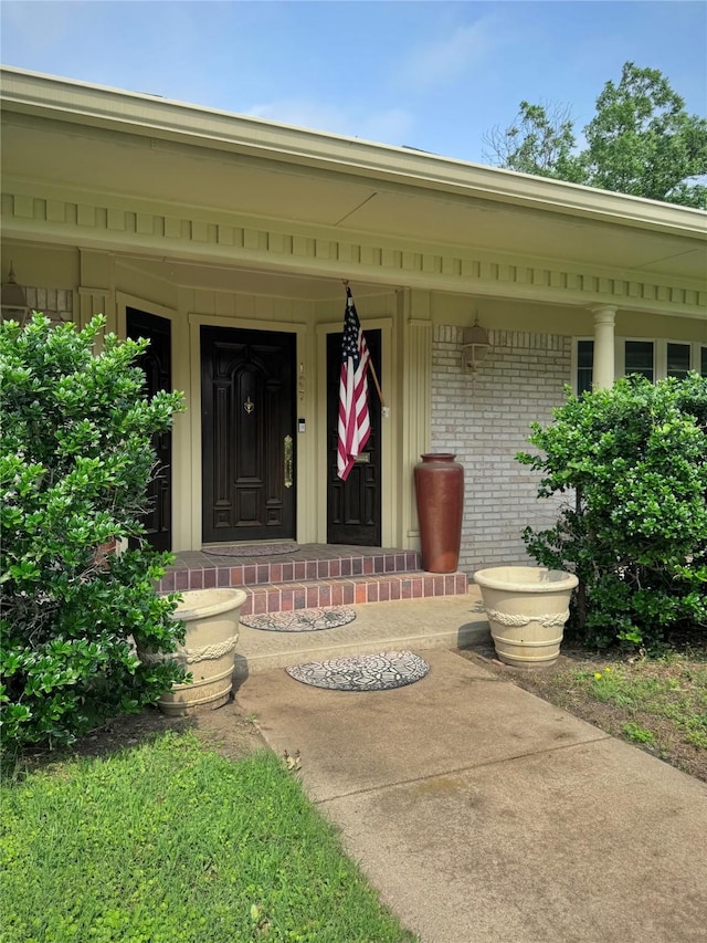 property entrance with a porch and brick siding