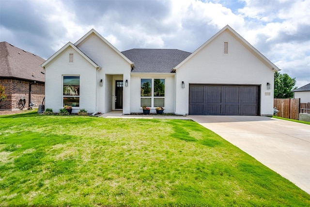 modern inspired farmhouse featuring fence, a front yard, stucco siding, an attached garage, and driveway