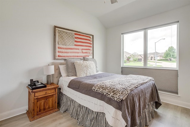 bedroom with baseboards, light wood-style flooring, and lofted ceiling
