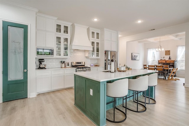 kitchen featuring light wood-style flooring, custom exhaust hood, white cabinets, and stainless steel appliances