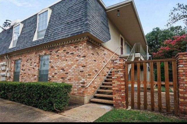 5315 Fleetwood Oaks Ave Unit 260, Dallas, TX 75235 - view of side of home featuring stairway, brick siding, roof with shingles, and mansard roof