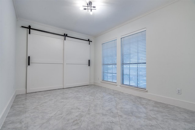 empty room featuring crown molding, baseboards, and a barn door