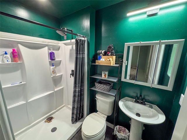 bathroom with a sink, a shower stall, and toilet