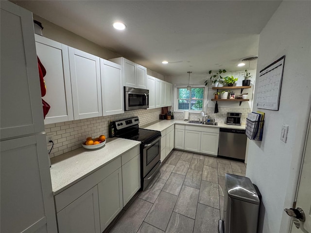 kitchen featuring light countertops, appliances with stainless steel finishes, a sink, and tasteful backsplash
