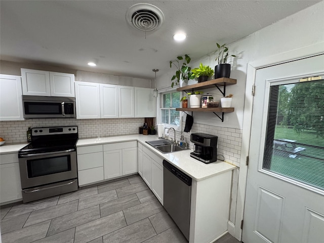 kitchen featuring visible vents, tasteful backsplash, a sink, white cabinets, and stainless steel appliances