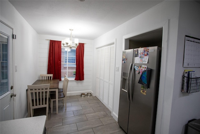 kitchen with stainless steel fridge, baseboards, and an inviting chandelier