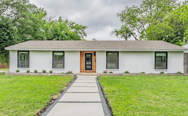ranch-style house featuring brick siding, a shingled roof, and a front yard