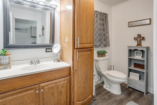 bathroom with vanity, ornamental molding, toilet, and wood finished floors
