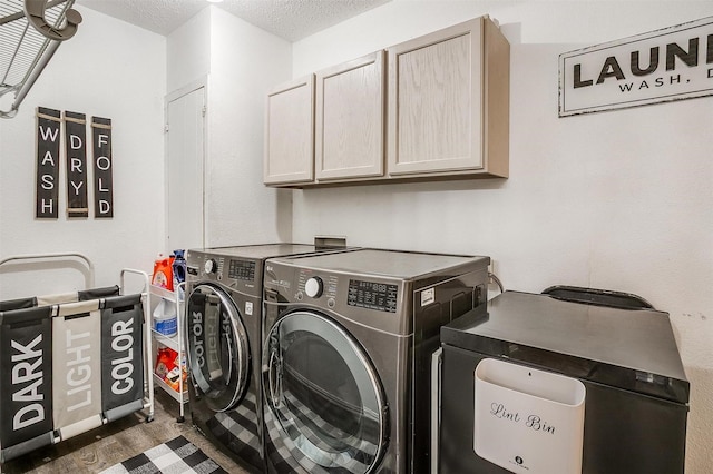 clothes washing area featuring wood finished floors, a textured ceiling, cabinet space, and washing machine and dryer