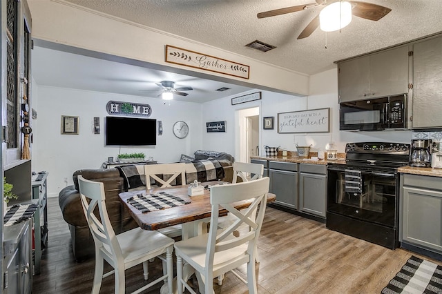 dining area with a ceiling fan, light wood-type flooring, a textured ceiling, and visible vents