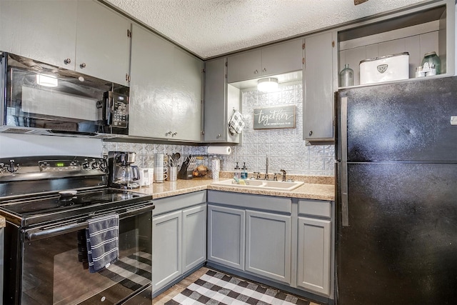 kitchen with light countertops, gray cabinetry, a sink, and black appliances