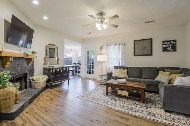 living area with ceiling fan, a fireplace, recessed lighting, wood finished floors, and visible vents