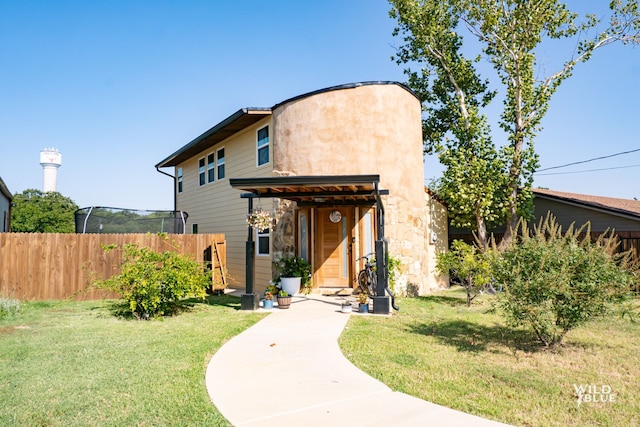 view of front of home with fence, stone siding, and a front lawn
