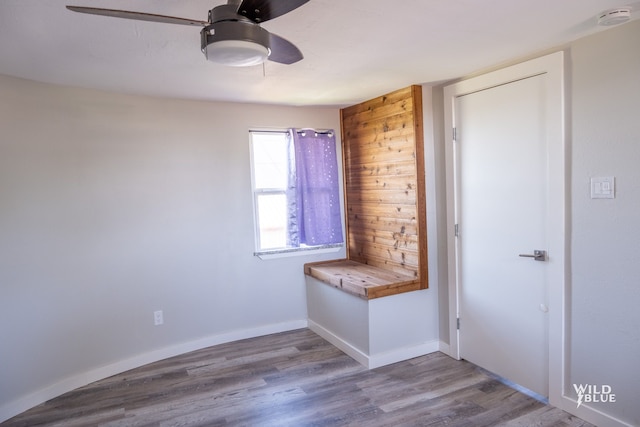 spare room with baseboards, ceiling fan, and wood finished floors