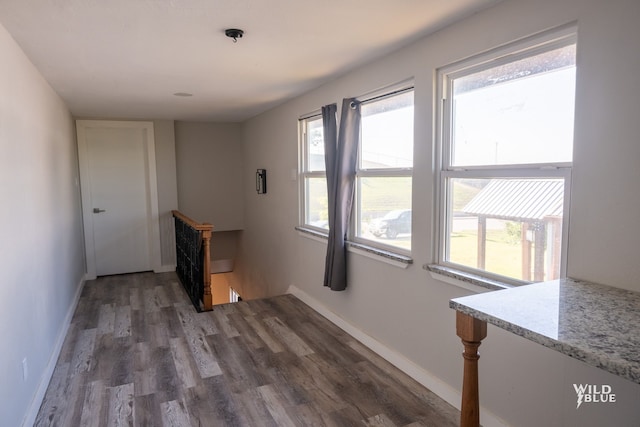 interior space with baseboards, an upstairs landing, and wood finished floors