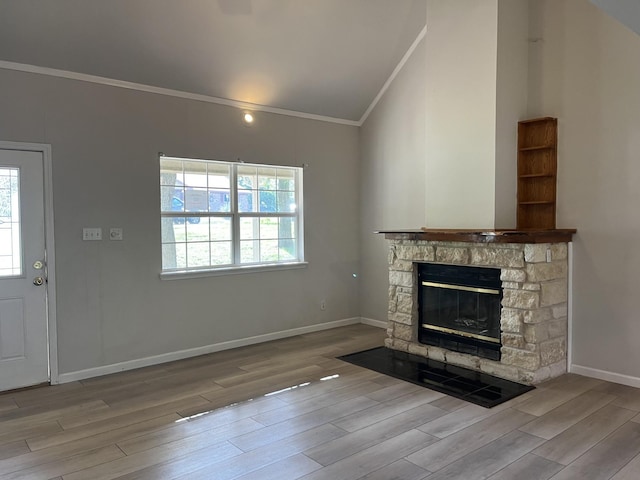 unfurnished living room with crown molding, a fireplace, wood finished floors, baseboards, and lofted ceiling