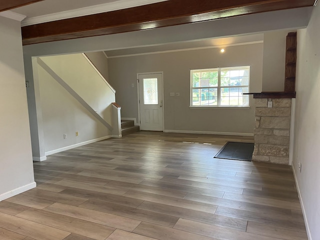 foyer featuring baseboards, ornamental molding, wood finished floors, and stairway