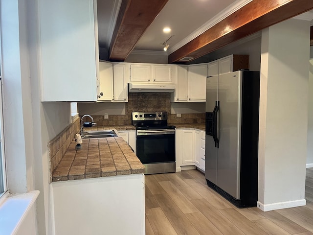 kitchen featuring crown molding, light wood-style floors, under cabinet range hood, a sink, and appliances with stainless steel finishes