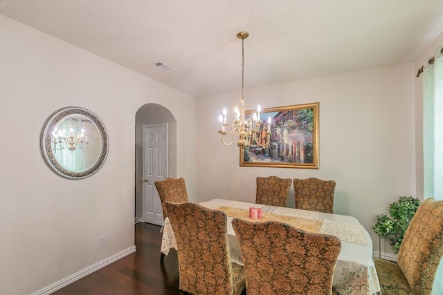 dining space featuring arched walkways, a chandelier, dark wood finished floors, baseboards, and visible vents