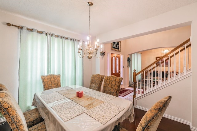 dining room featuring arched walkways, stairs, wood finished floors, and a notable chandelier