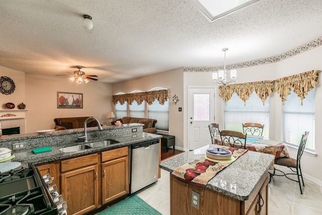 kitchen featuring brown cabinets, appliances with stainless steel finishes, a sink, a textured ceiling, and open floor plan