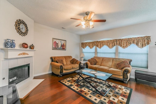 living room featuring visible vents, a ceiling fan, a textured ceiling, and wood finished floors