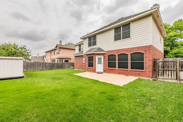 rear view of property with a patio, brick siding, a lawn, a storage shed, and an outbuilding