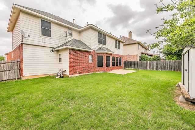 back of house featuring a lawn, brick siding, and a fenced backyard