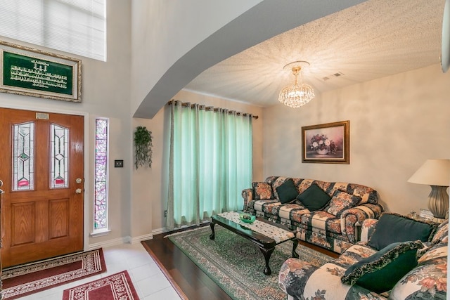 tiled living area featuring visible vents, arched walkways, plenty of natural light, and a notable chandelier