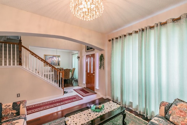 entrance foyer featuring an inviting chandelier, arched walkways, and stairs
