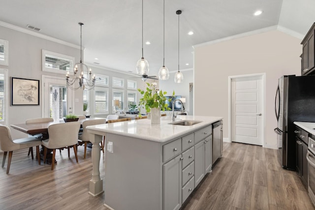 920 Plaza Ln, Argyle, TX 76226 - kitchen with stainless steel appliances, ornamental molding, wood finished floors, light countertops, and a center island with sink