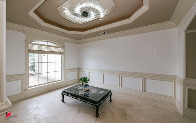 sitting room with a tray ceiling, ornamental molding, a wainscoted wall, and a decorative wall