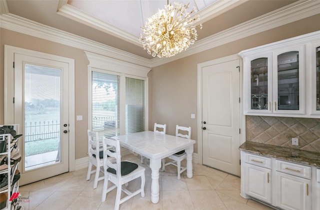 dining room featuring light tile patterned flooring, a tray ceiling, an inviting chandelier, and ornamental molding