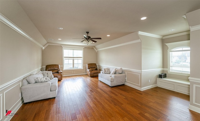 living room with a ceiling fan, wainscoting, wood finished floors, and a decorative wall