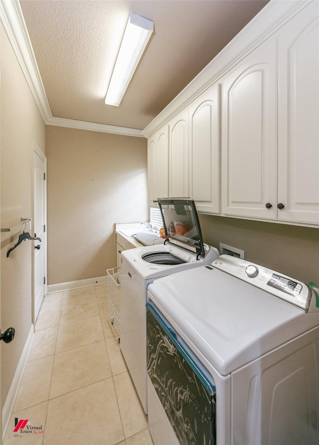 clothes washing area with cabinet space, light tile patterned flooring, washing machine and clothes dryer, baseboards, and ornamental molding
