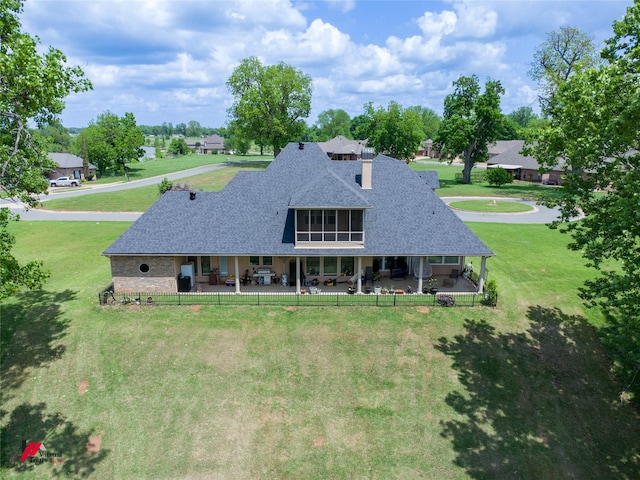 back of property with a lawn, a chimney, a patio area, and roof with shingles