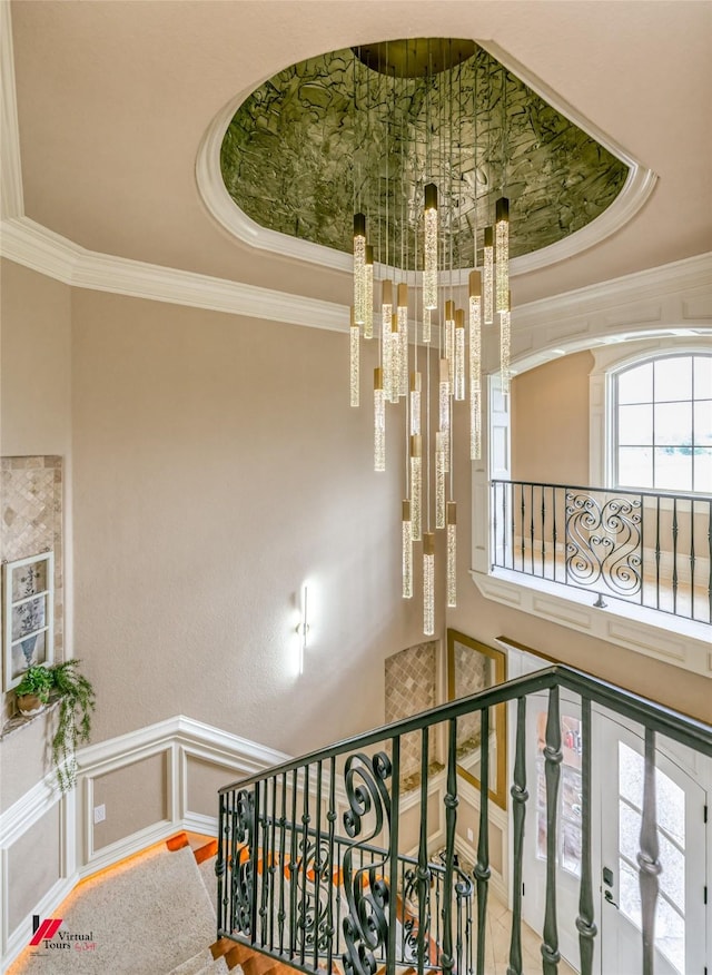stairs with ornamental molding, a notable chandelier, and a tray ceiling
