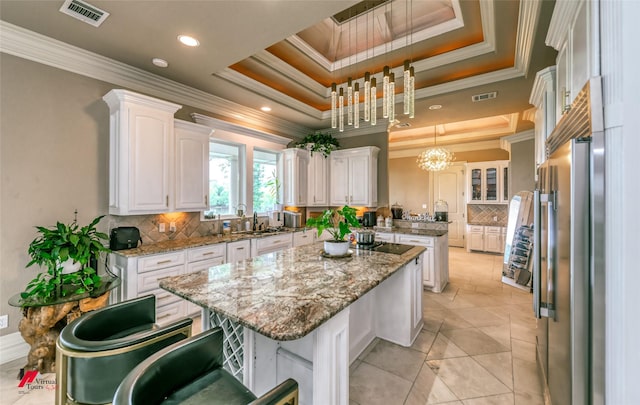 kitchen featuring crown molding, backsplash, white cabinets, and a raised ceiling