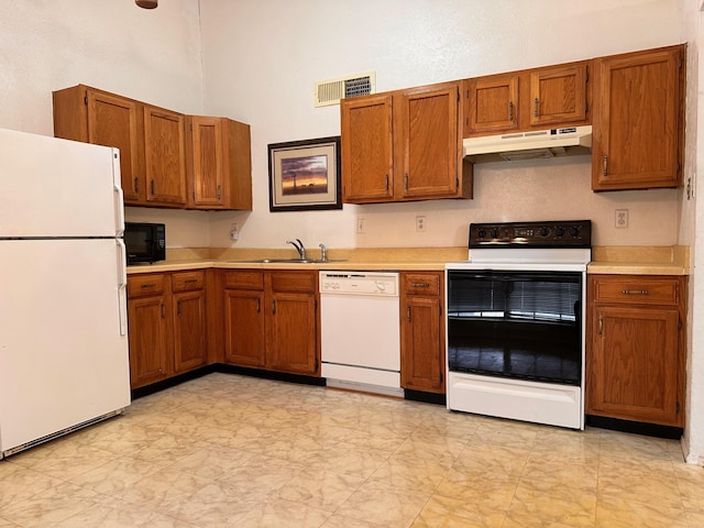 4757 China Rose Dr, Fort Worth, TX 76137 - kitchen with brown cabinetry, under cabinet range hood, white appliances, and visible vents