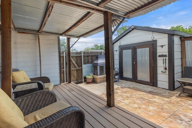 deck with fence, an outbuilding, and a patio area