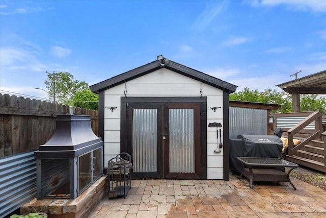 view of shed with fence and a fireplace