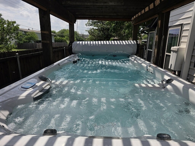 view of pool with a hot tub and fence