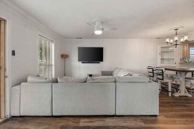 living area with ornamental molding, ceiling fan with notable chandelier, and wood finished floors