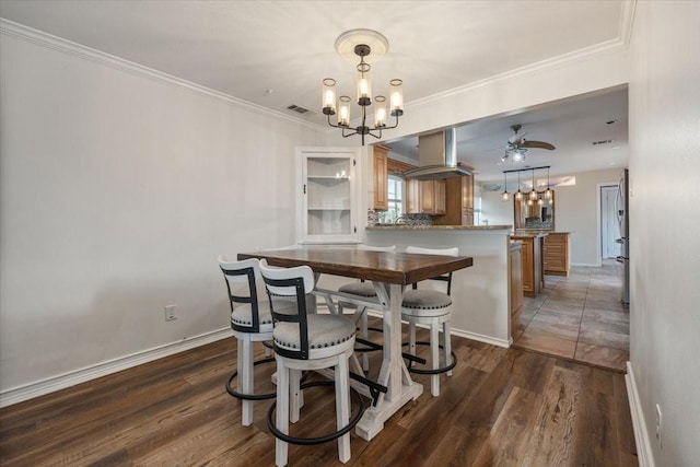 dining room with visible vents, crown molding, wood finished floors, baseboards, and ceiling fan with notable chandelier