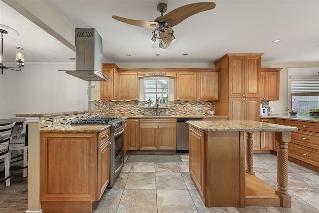 kitchen with a kitchen bar, island range hood, appliances with stainless steel finishes, a sink, and ceiling fan with notable chandelier